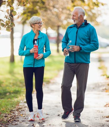 55+ couple walking together with water bottles