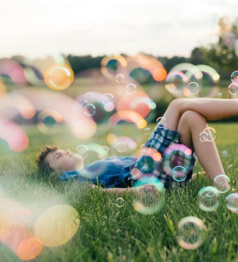 A boy playing in bubbles on a warm summer day