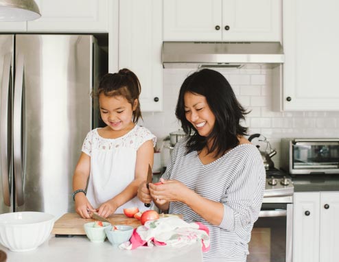 Mom And Daughter Making A Snack Together In Kitchen